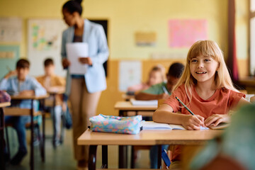 Happy elementary student learning on class at school.