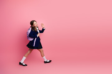Fototapeta na wymiar Happy student in formal school uniform on pink background, waving hand, education and back to school concepts