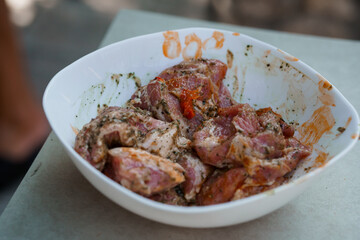 Raw Lamb Marinating in White Bowl Outdoors: Close-Up Culinary Preparation Scene with Herb Spices...