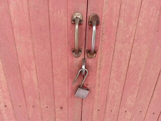Locked Pink Wooden Door with Metal Handles and Padlock