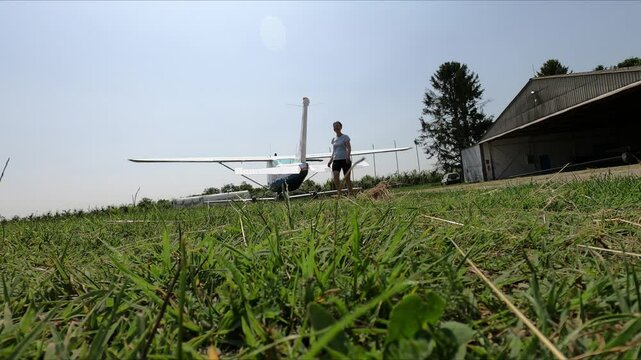 An athletic looking woman walks away from a small plane - a Cessna 182