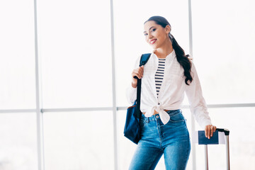 Charming woman smiling with luggage and passport at the airport, ready for an exciting travel...