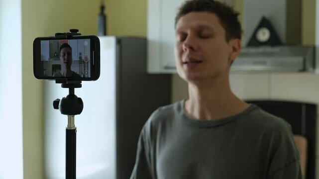 Man recording personal development vlog at home kitchen. Sharing self-growth ideas and mindful morning routine.