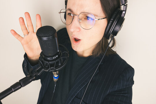 Female caucasian young adult singing into microphone with headphones in studio setting