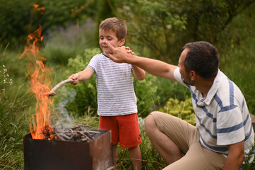 father and son making fire outdoors. Fire safety. Forest fire. Time with kids, outdoor recreation, barbecue picnic. Father's Day