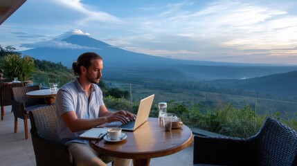 Fototapeta premium Digital nomad working on laptop from mountain cafe terrace, scenic view, coffee, and notebook by side
