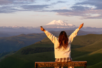 Mountains Woman Sunset: Girl enjoys Mount Elbrus view at sunrise, seeking happiness and freedom in nature.