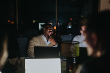 A group of business coworkers work late into the night, collaborating on a project. The dimly lit...