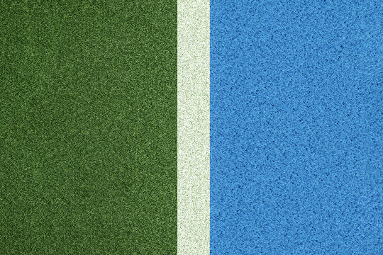 Top view of tennis court surface with green grass and blue hard court divided by white line