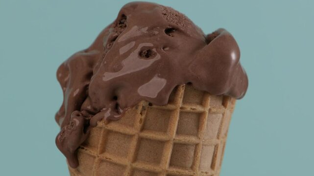 melting cacao gelato in waffer coner blue background close up