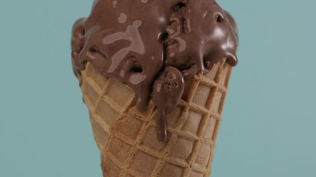 melting cacao gelato in waffer coner blue background close up food