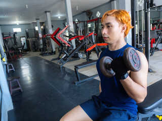 Asian Indonesian man plays dumbbell exercise to train arm endurance to strengthen and tighten...