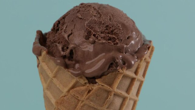melting chocolate ice cream in waffer coner blue background