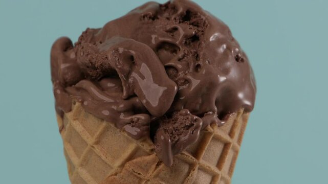 melting chocolate ice cream in waffer coner blue background zoom