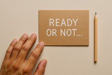 Naklejka na ściany i meble Hand reaching toward brown card with ready or not message and pencil on beige desk, concept of decision and preparation