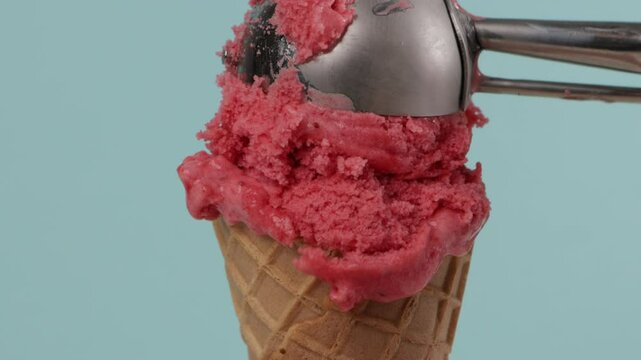 put pink sorbet in waffer coner blue background summer food