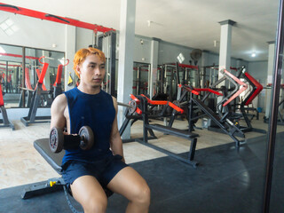 Asian Indonesian man plays dumbbell exercise to train arm endurance to strengthen and tighten...
