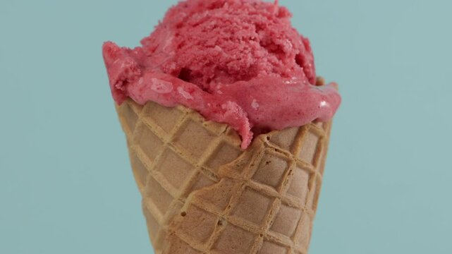 put pink sorbet in waffer coner blue background close up food