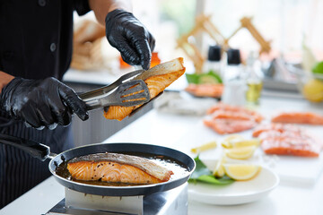 chef cooking salmon steaks in the kitchen