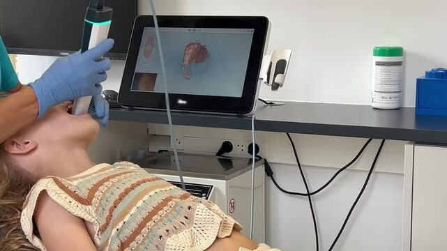 An orthodontist uses a modern 3D scanner to create a detailed 3D model of a child's mouth and teeth