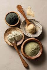 Flat lay of wooden spoons and bowls containing powdered ashwagandha, maca, spirulina, reishi, functional wellness products