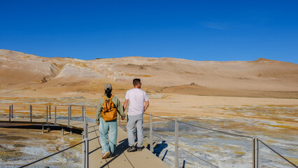 Exploring the Hverir geothermal landscapes of Iceland with a partner on a sunny day