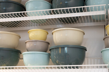 Assorted stacked mixing bowls on metal shelves in kitchen storage