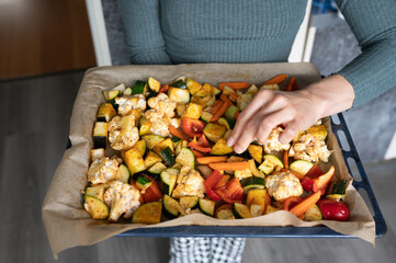 Female preparing colorful baked vegetables in kitchen