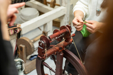 Distaff Day Caucasian female adult spinning yarn on a traditional spinning wheel