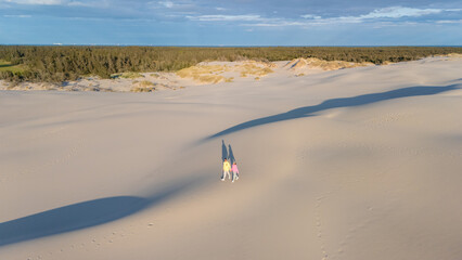 Walking on golden sand dunes in Denmark under a bright blue sky with gentle cloud patterns