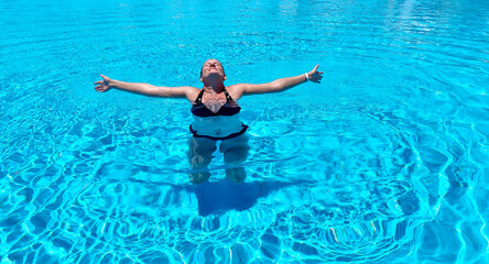 Young woman in the pool spread her arms in the blue water enjoying her summer vacation. Summer travel, hotel vacation or events