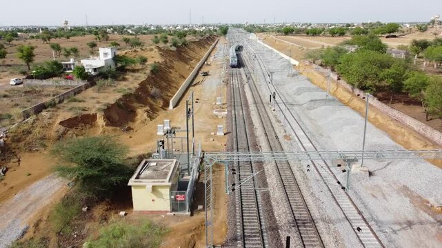 Drone or Aerial view moving away from a running Train from behind, in the Thar Desert of Rajasthan(India), along with multiple Railway tracks 