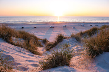 Breathtaking sunset over the sandy dune beach in Denmark with coastal vehicles at dusk