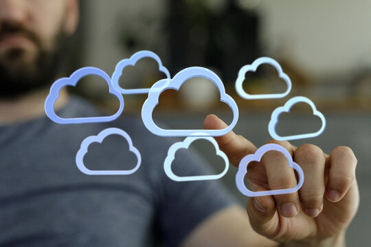 Image depicts a man interacting with digital cloud icons, representing cloud computing and data storage.