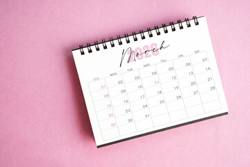 Top view of March 2026 desk calendar on pink pastel background.