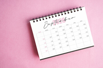 Top view of September 2026 desk calendar on pink pastel background.