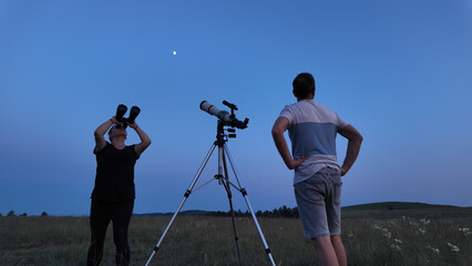 Amateur astronomers using telescope and binoculars for watching stars, Moon, planets and other...