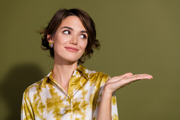 Confident young businesswoman presenting an idea with a khaki background, wearing a stylish yellow...