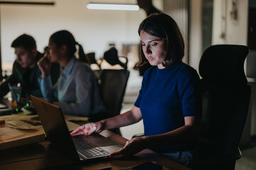 A dedicated team of business coworkers working late hours in a dimly lit office. The image captures...