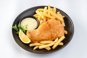fish and chips served with french fries and tartar sauce with sliced lemon on plate isolated on...