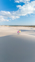 Couple walking hand in hand on a serene beach in Denmark under a bright blue sky