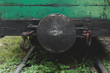 Close-up view of an antique train coupling on overgrown tracks surrounded by lush green vegetation...