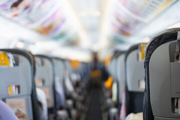 Inside commercial airplane, passengers sit calmly in economy class. Selective focus of the aisle, with blurred seats creating depth. It shows air travel, aviation lifestyle, or transportation scenes.