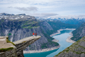 Stunning hikers enjoy breathtaking view at Trolltunga cliff in Norways idyllic landscape