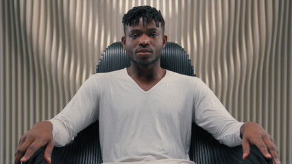 Futuristic confident serious gamer programmer hacker African American man guy male sitting in chair in futurism modern room studio in chair looking at camera 3D computer graphics AI network concept