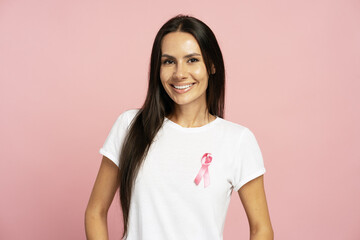Smiling woman wearing pink ribbon for breast cancer awareness month