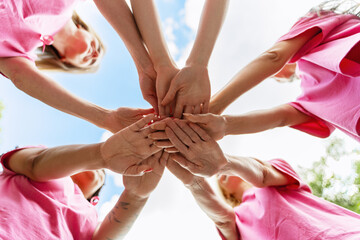 Women joining hands for breast cancer awareness, showing unity and support