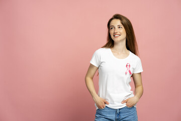 Woman smiling and showing pink ribbon for breast cancer awareness