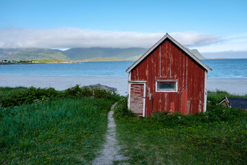 Charming red cabin by the beach in Norway with stunning coastal views and lush greenery