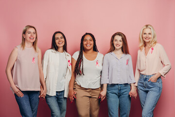 Obraz premium Diverse women holding hands showing pink ribbons for breast cancer awareness